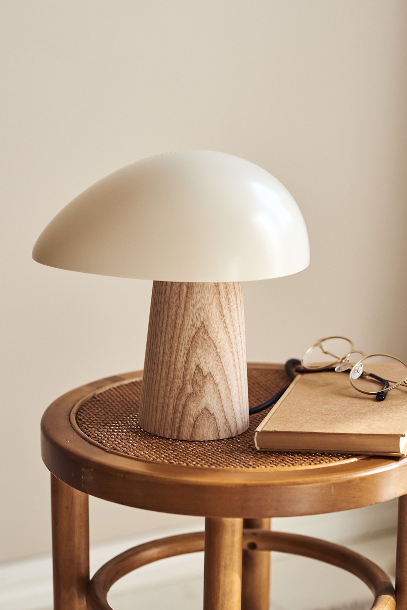 La lámpara de sobremesa Night Owl de Fritz Hansen se apoya en un taburete de madera
con un libro y unas gafas de lectura.