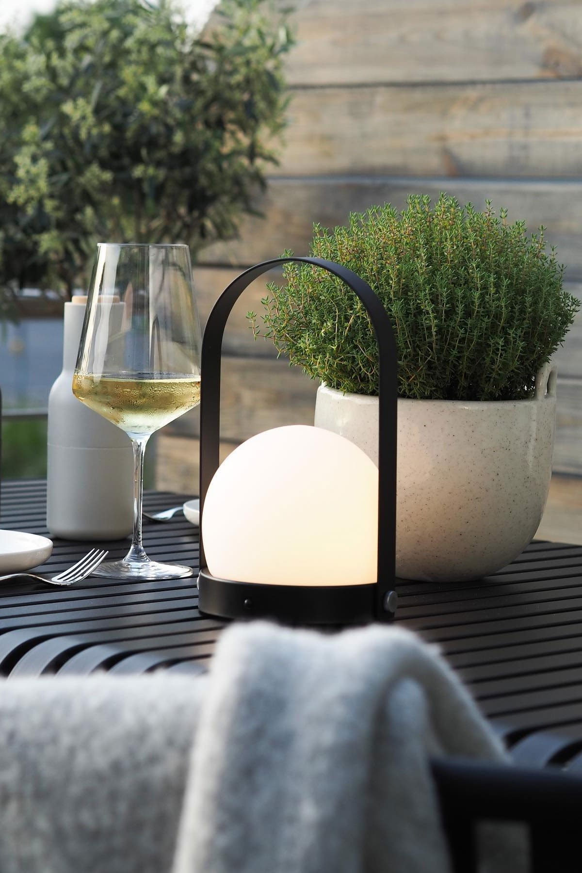 La lámpara portátil Carrie de Audo Copenhagen y la maceta Speckle de Ferm Living sobre la mesa Palissade de HAY en la terraza de @wohngluecksieben.