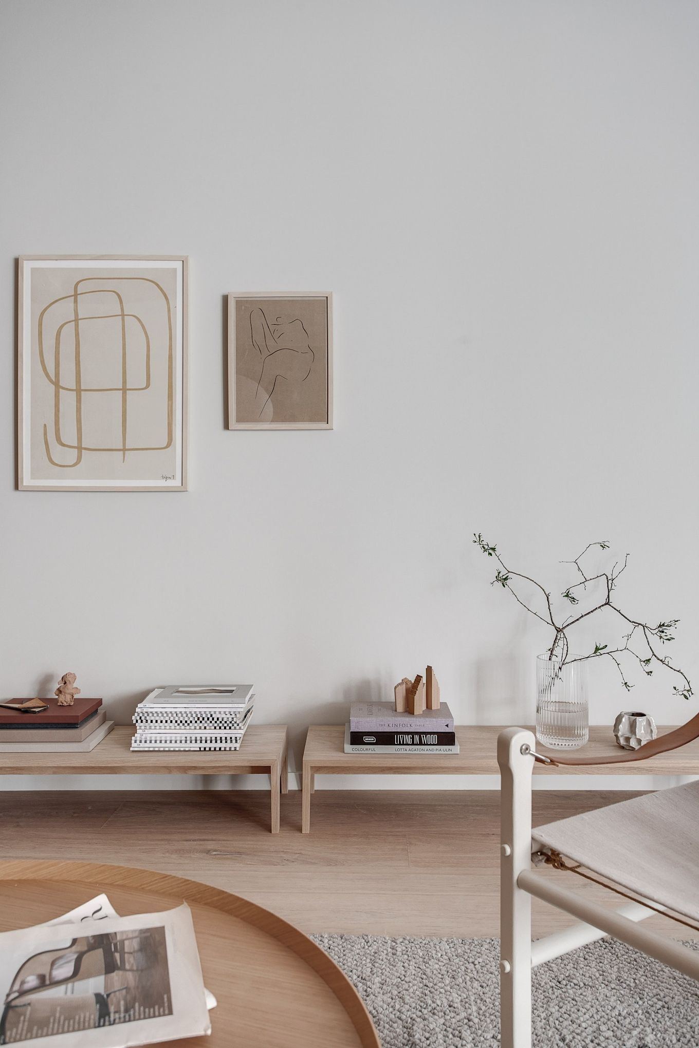 Sala de estar decorada en el estilo Japandi con muebles bajos de madera clara y obras de arte con líneas limpias.