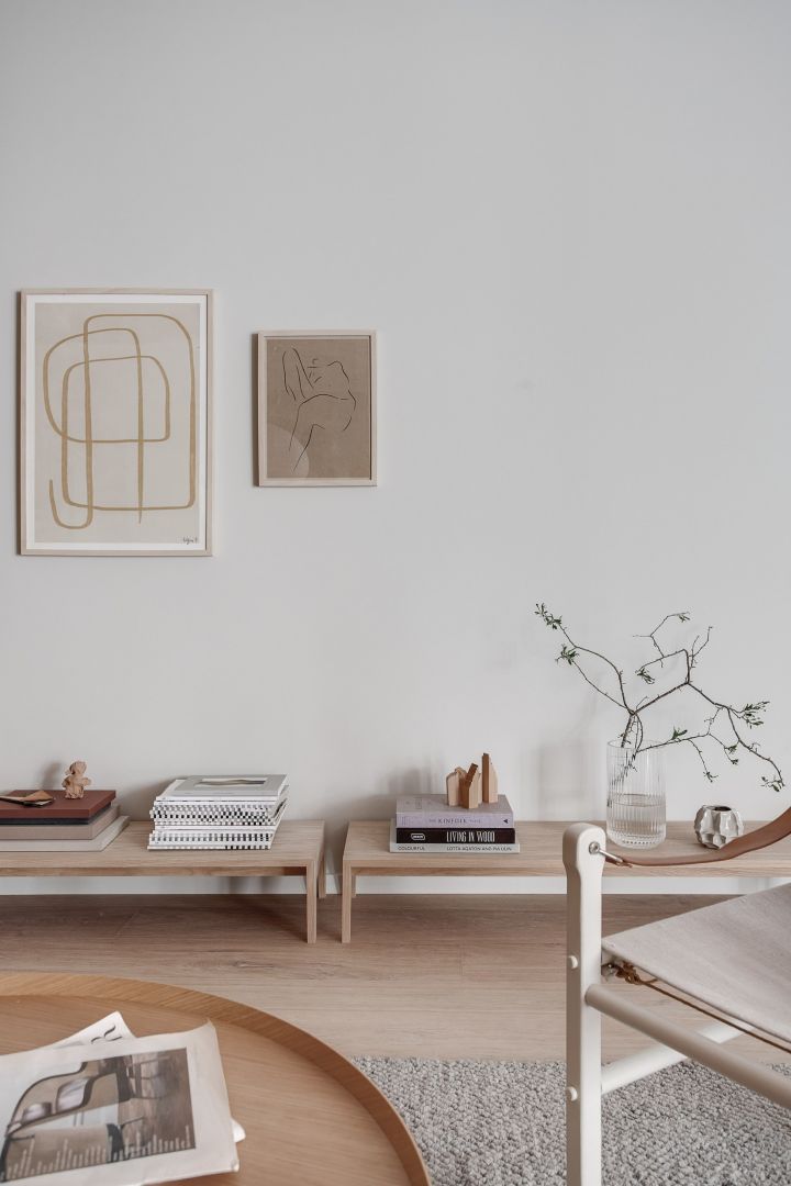 Sala de estar decorada en el estilo Japandi con muebles bajos de madera clara y obras de arte con líneas limpias.