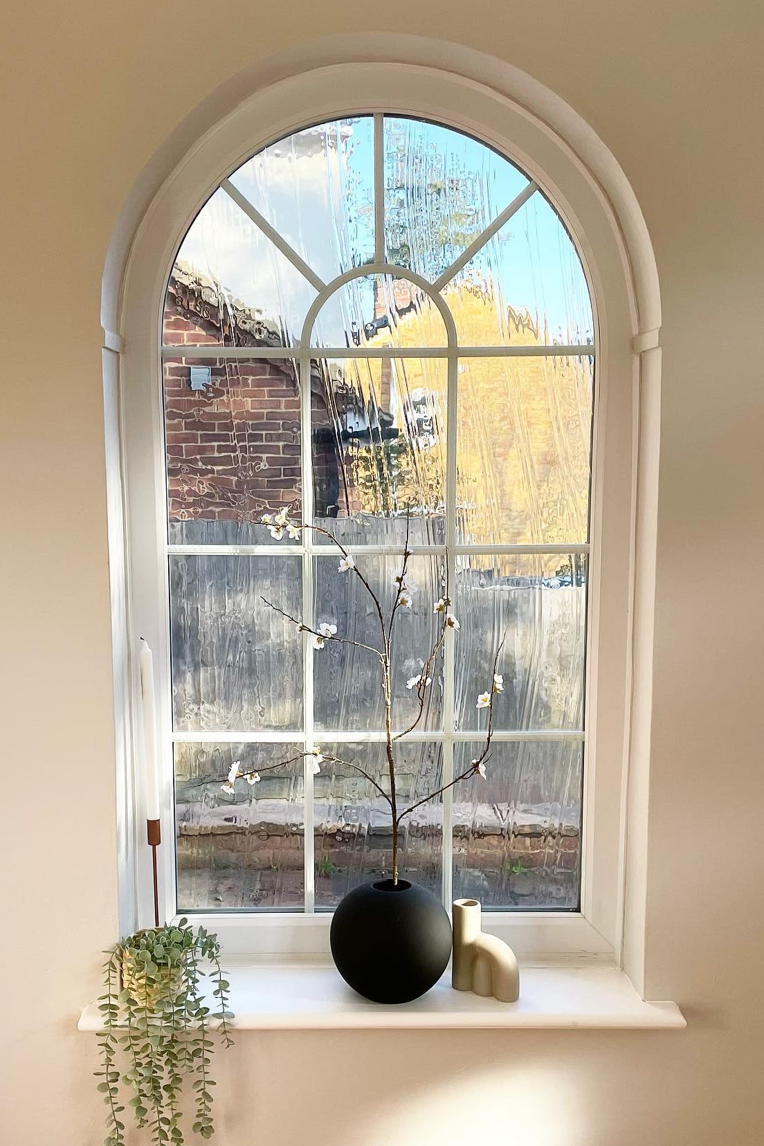 Aquí puedes ver la bonita ventana arqueada con alféizar de @abrysonhouse, que está decorada con candelabros y el jarrón de bolas negras de Cooee Design con flores primaverales.