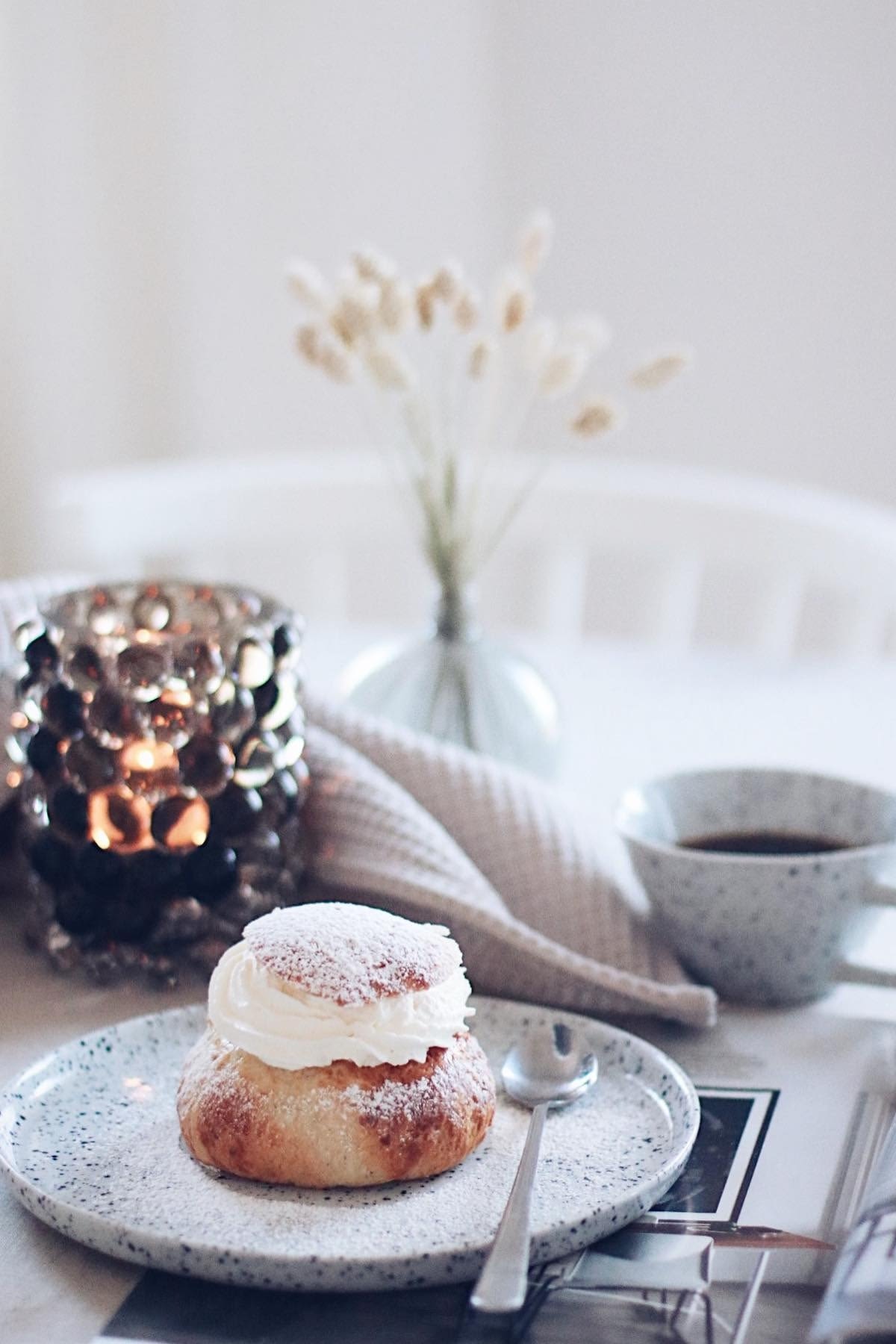 El semla es uno de los pasteles favoritos de Suecia. Aquí puedes ver uno en un plato Poppi de Olsson & Jensen, frente a una taza Poppi, en la casa de la influencer sueca @picsbyellen.