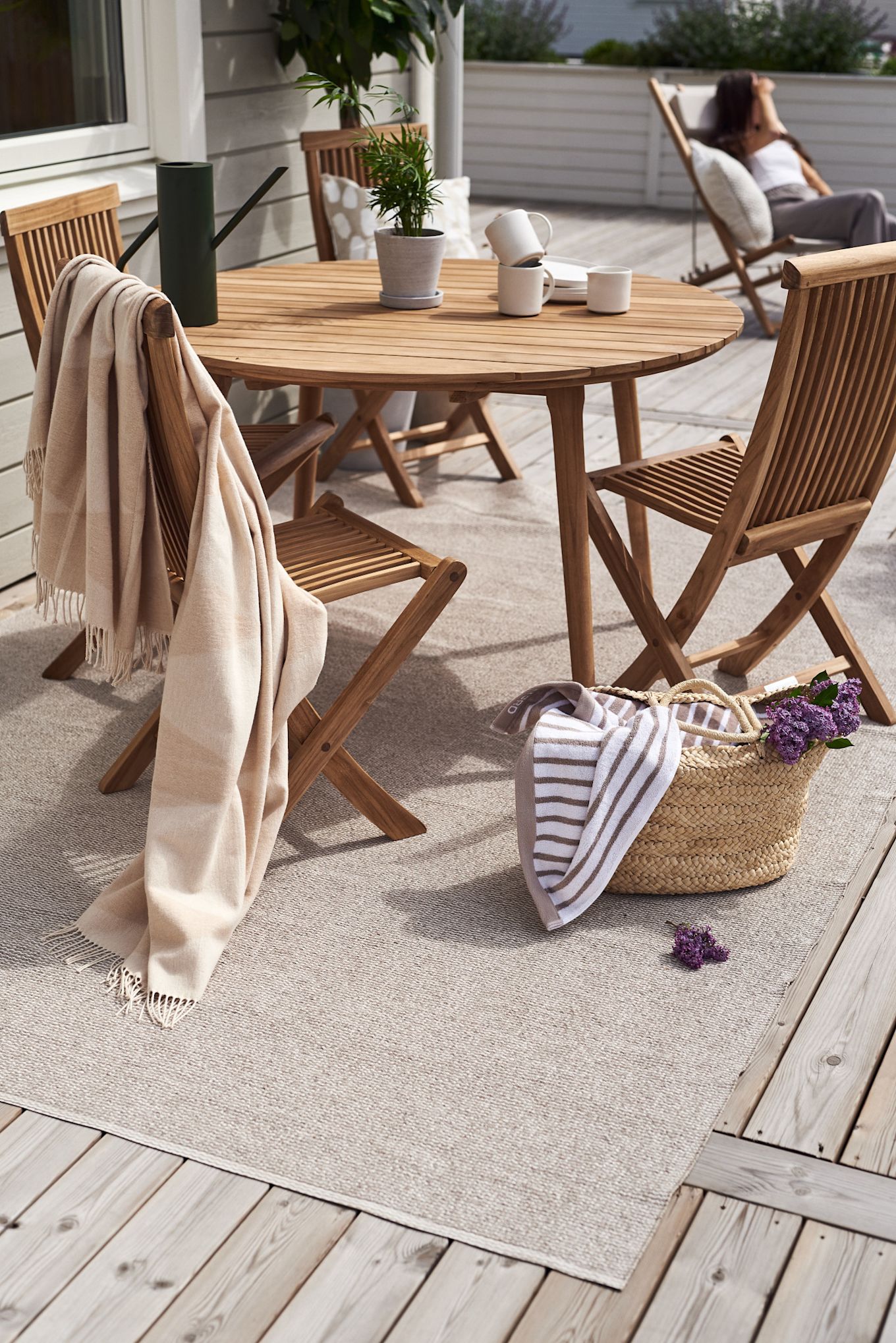 Una terraza con muebles de madera: el set de balcón Aneboda de 1898 y la alfombra de algodón Rime de Scandi Living sobre la alfombra plástica Mellow