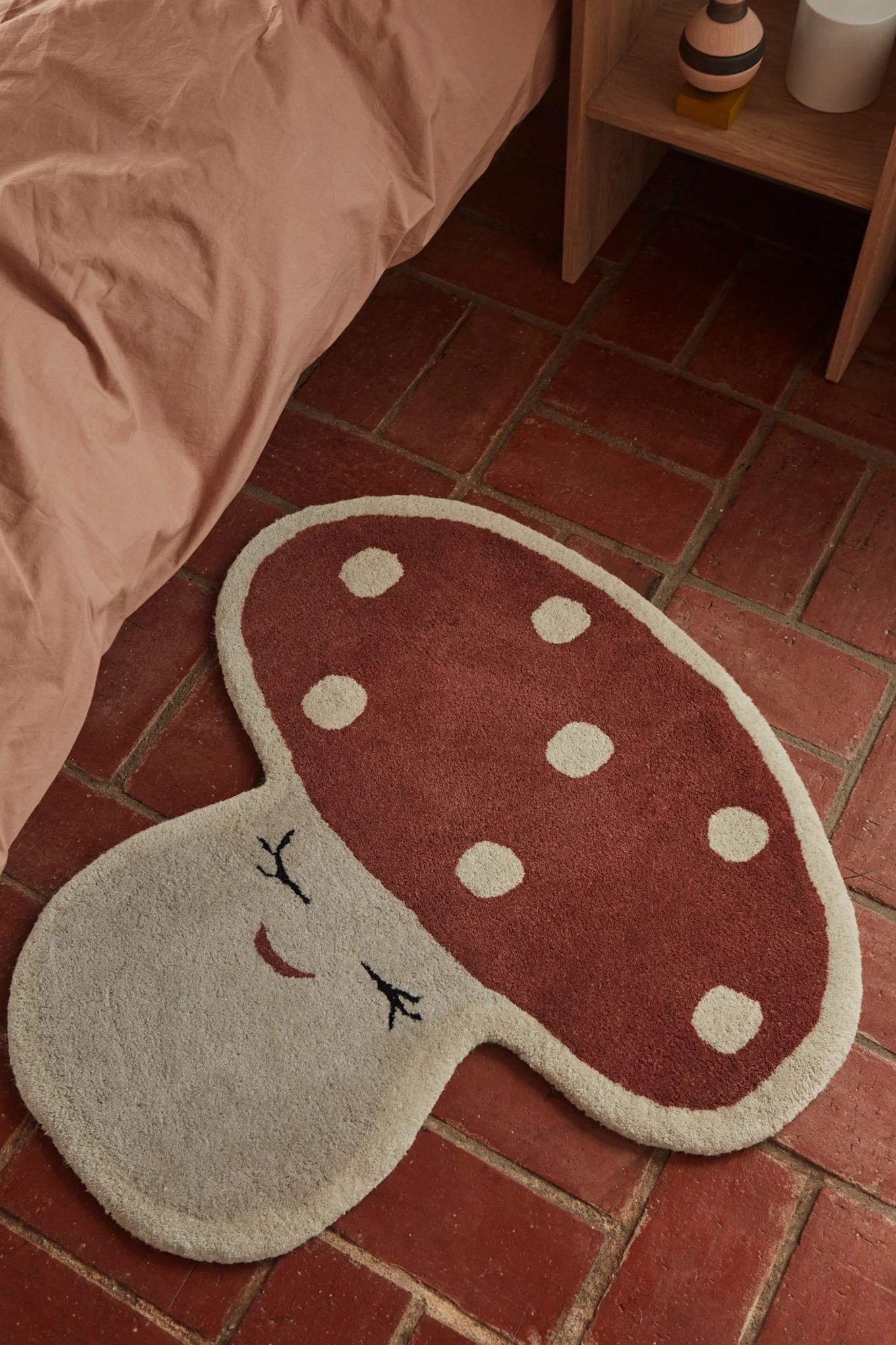 Una alfombra divertida para la habitación infantil es la alfombra Malle Mushroom de OYOY, con forma de seta y hecha de una suave mezcla de lana y algodón con una superficie rugosa para una sensación extra suave.