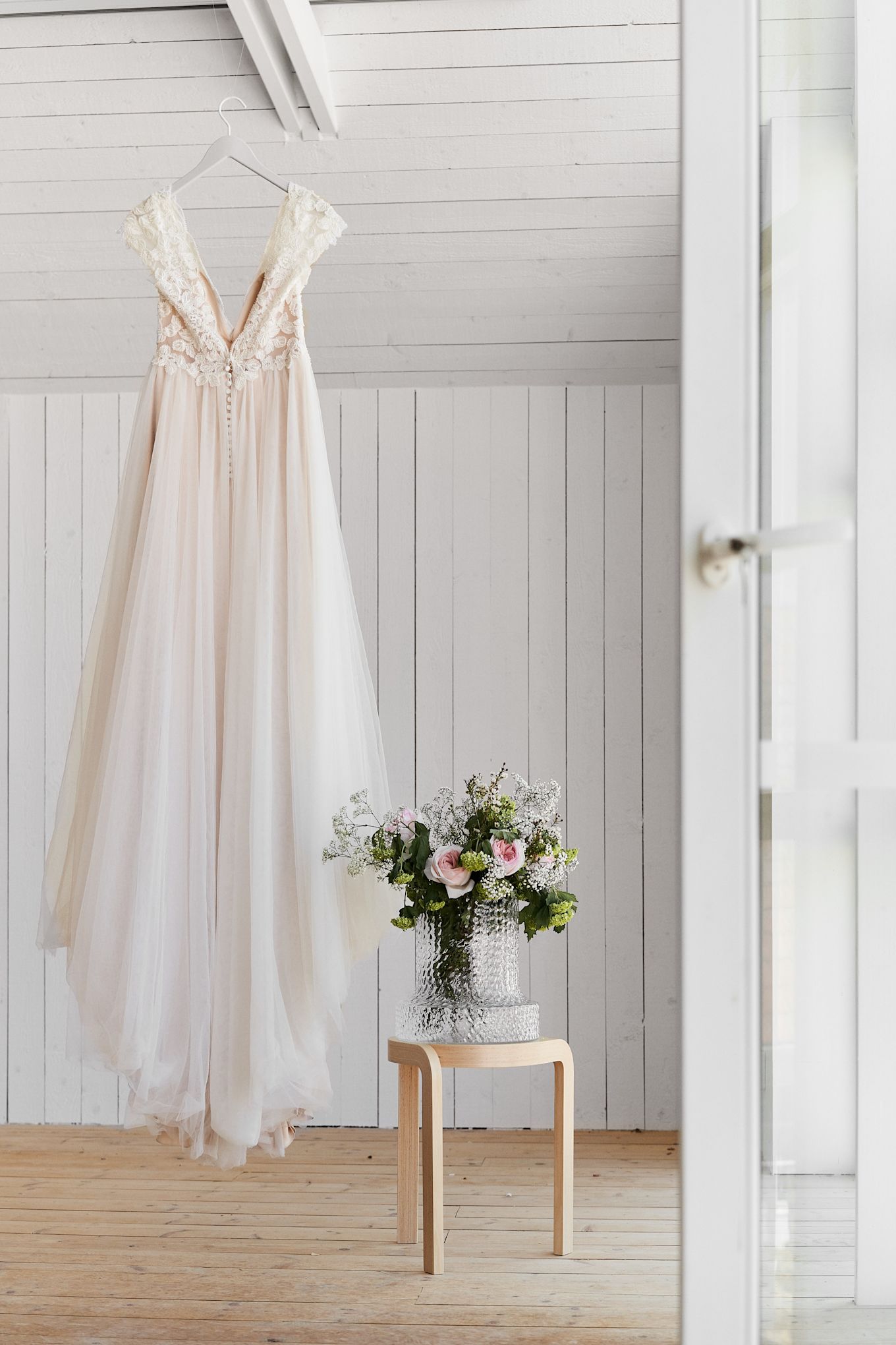 Las ideas de boda únicas deben fotografiarse para recordarse. Llena jarrones con bonitas flores
para realzar tus fotos, aquí ves un vestido de novia colgado junto a un taburete de madera y un
jarrón.