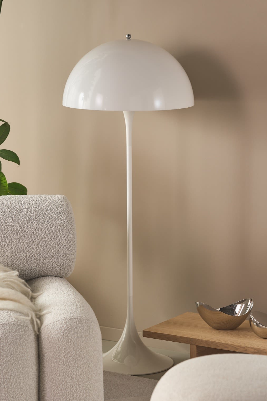 Renueva tu hogar con modernas lámparas de pie. Aquí ves la lámpara de pie Panthella en una sala de estar beige con plantas verdes y muebles robustos.