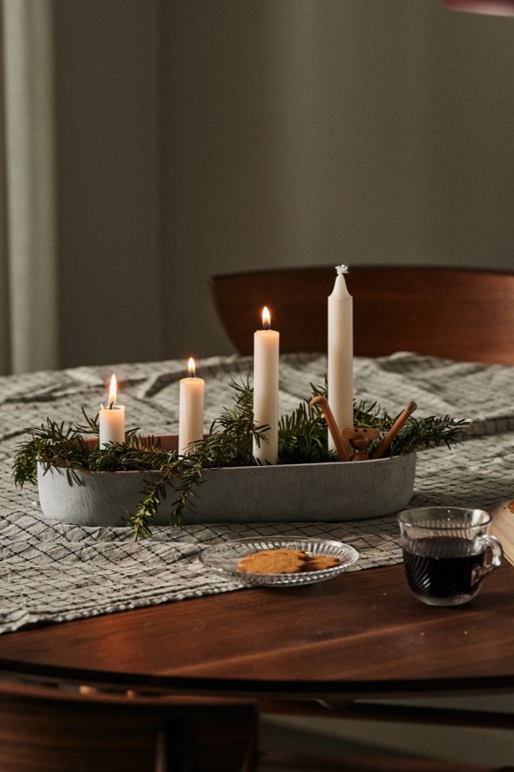 Aquí puedes ver un tradicional portavelas navideño escandinavo sobre la mesa, acompañado de pan de jengibre y una taza de vino caliente.