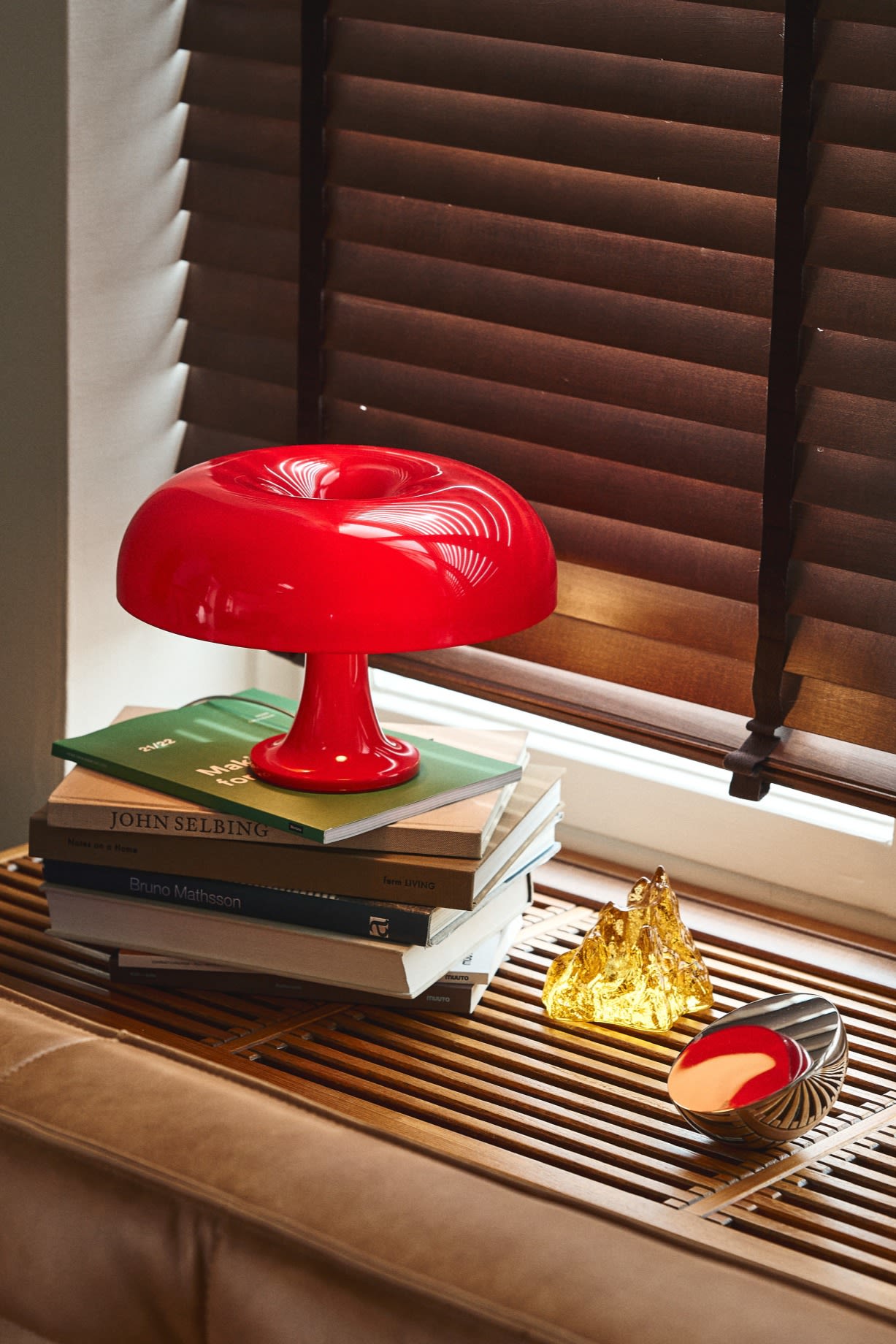 Actualiza tu hogar con ideas de iluminación moderna como la favorita de Instagram Nessino en rojo de Artemide. Vista aquí en un alféizar de ventana de madera con un portavela amarillo de Kosta Boda.