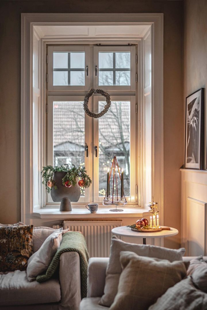 El influencer sueco @hannesmauritzson ha decorado su altísima ventana con una corona navideña, el alféizar está decorado con abetos verdes y el candelabro Season Extention de Georg Jensen.