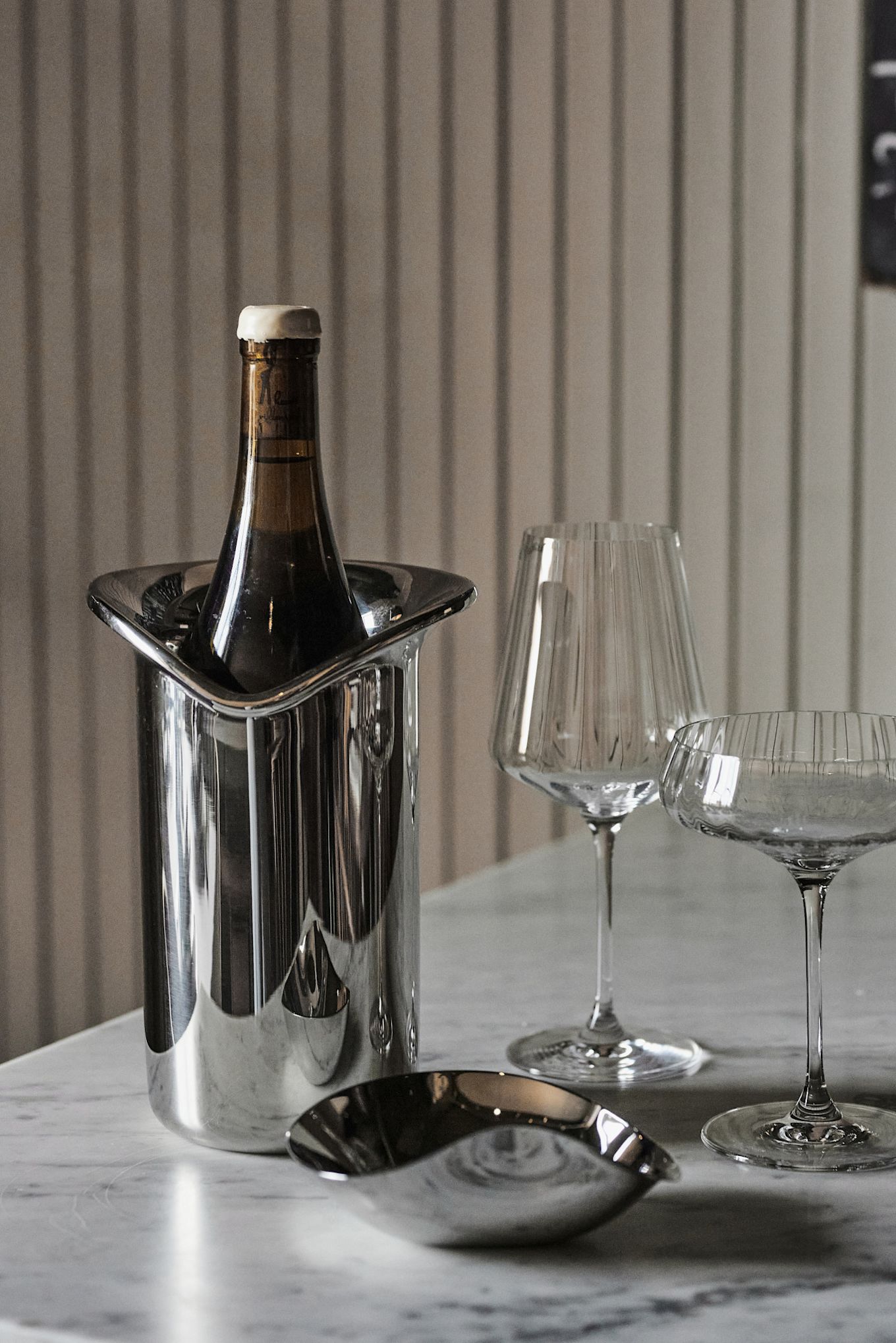 Aquí se muestra el enfriador de vino de Georg Jensen en una idea de decoración de mesa blanca, junto con los copas de vino y champán Bernadotte.