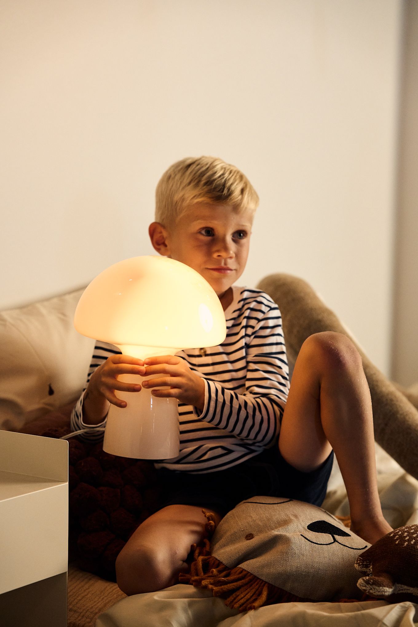 Equipar las habitaciones infantiles con iluminación es importante para cubrir las necesidades que existen, ya sea luz para jugar o para leer. Aquí la lámpara de mesa Fungo en color beige de Globen Lighting, una lámpara portátil con forma de seta.