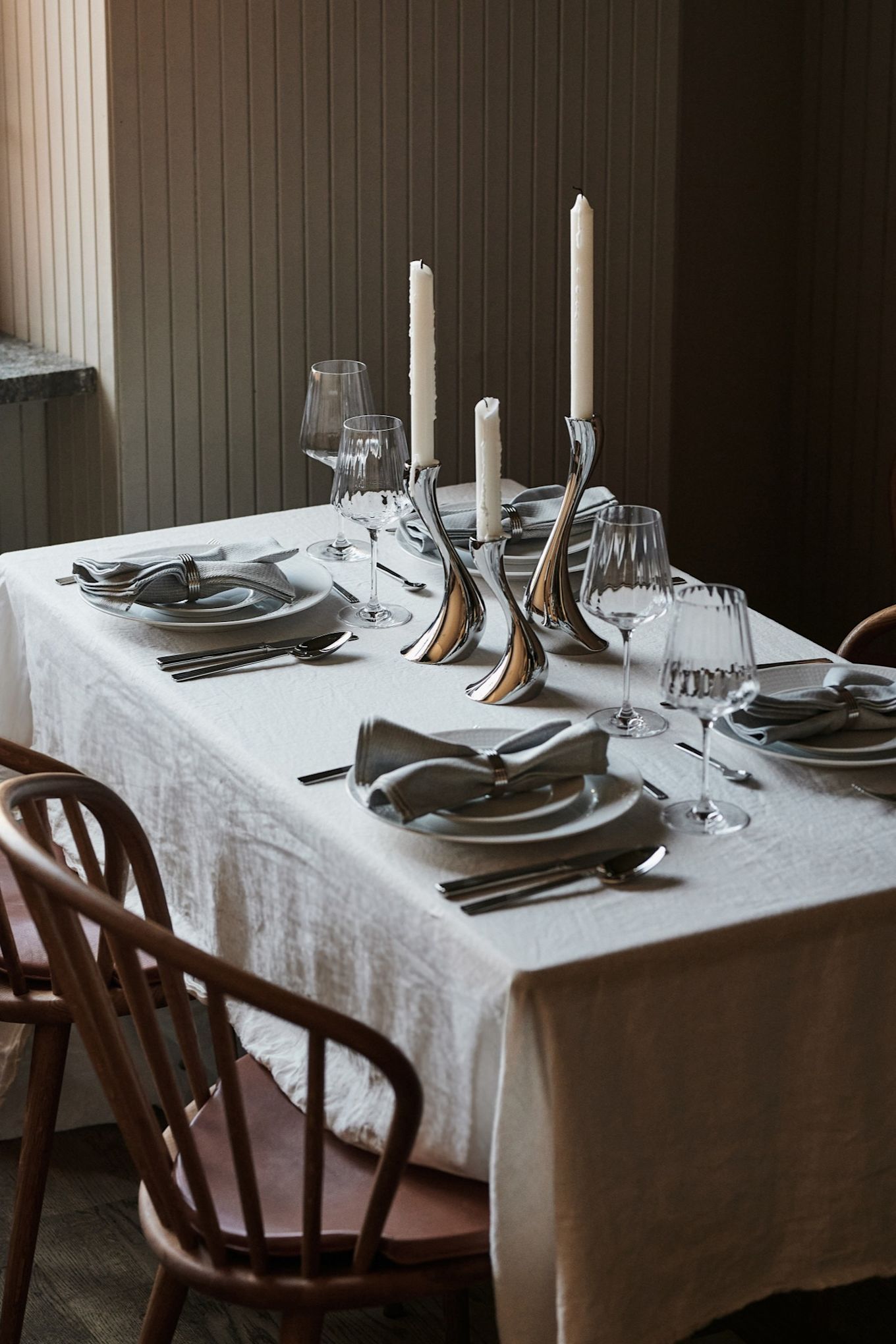 Una idea de decoración de mesa blanca con un mantel blanco nítido y detalles en cromo complementarios para una ambientación de estilo restaurante en casa.