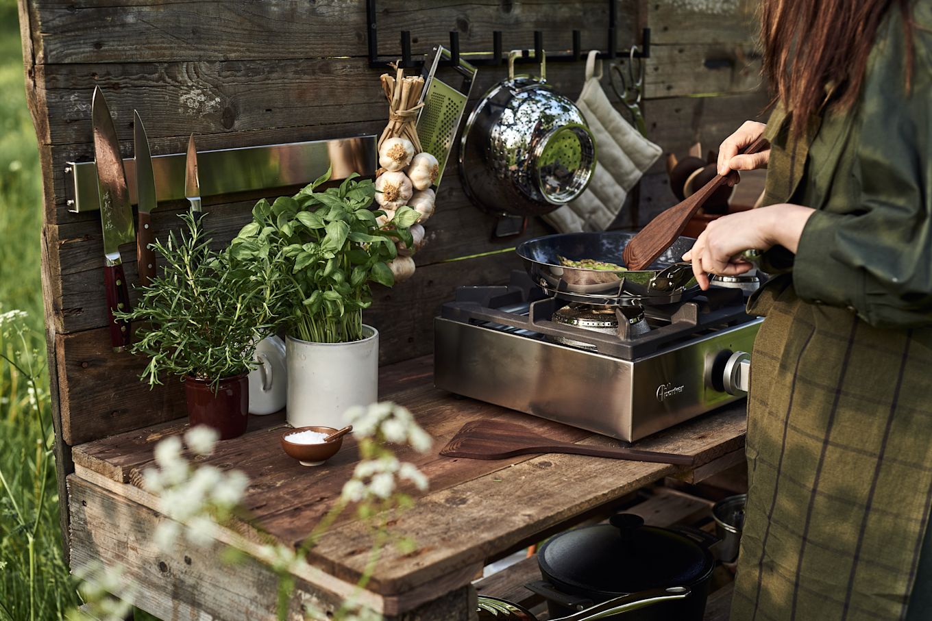 Una mujer cocinando al aire libre en una cocina exterior.