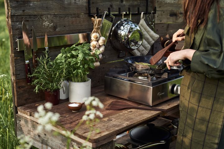 Una mujer cocinando al aire libre en una cocina exterior.