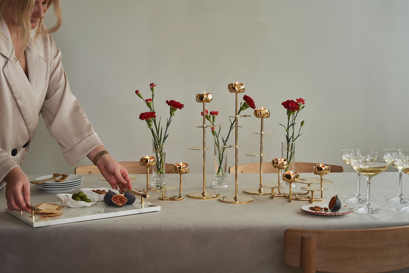 Las mesas elegantemente dispuestas son lo que nos gusta recoger de las tendencias escandinavas de interiorismo 2025. Aquí con candelabros de latón de Hilke, flores rojas y mantel de lino.