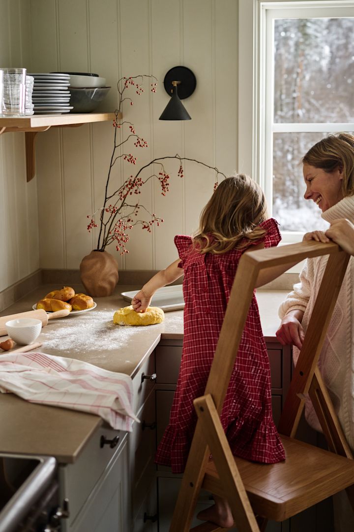 La Navidad sueca también se caracteriza por la repostería. Aquí puedes ver a una chica con un vestido rojo subida a la escalera de la cocina de la Design House Stockholm, amasando la masa para el lussekatter.