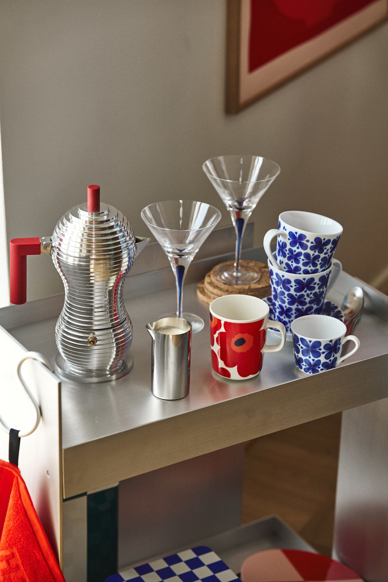 Aquí se ve un rinconcito de café cromado, de inspiración retro con tazas en rojo y azul junto con copas de cóctel en azul: el diseño interior nostálgico es una de las grandes tendencias según las tendencias de diseño de interiores de otoño de 2024.