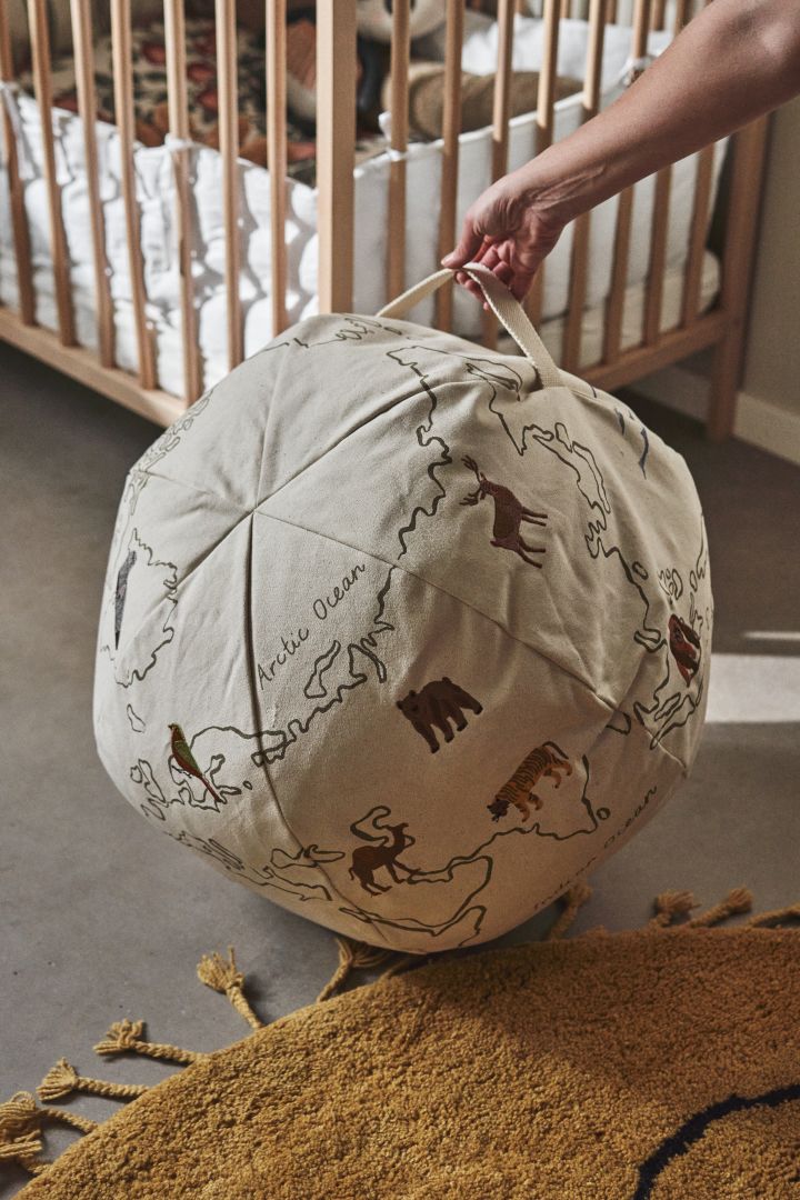 Otro detalle interior práctico y decorativo para la habitación infantil el puf The World de Ferm Living, con estampado bordado y práctico asa para colgar.