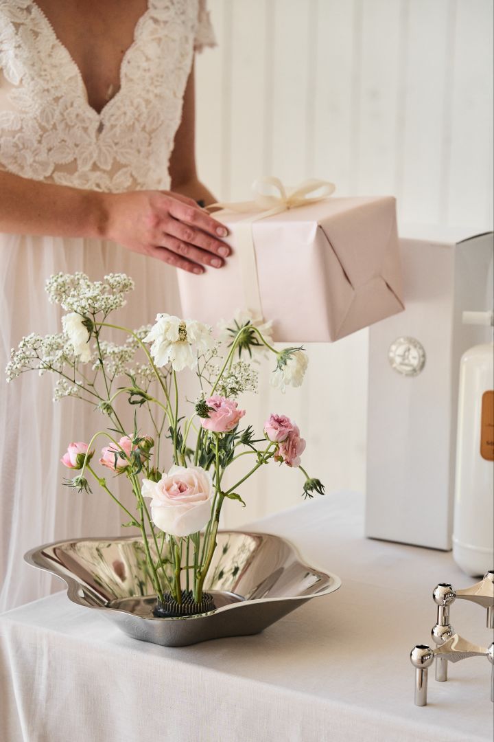 Aquí se ve el cuenco de acero inoxidable de Alvar Aalto utilizado como jarrón en una mesa de regalos de boda. Prueba esta idea única para el día de tu boda.