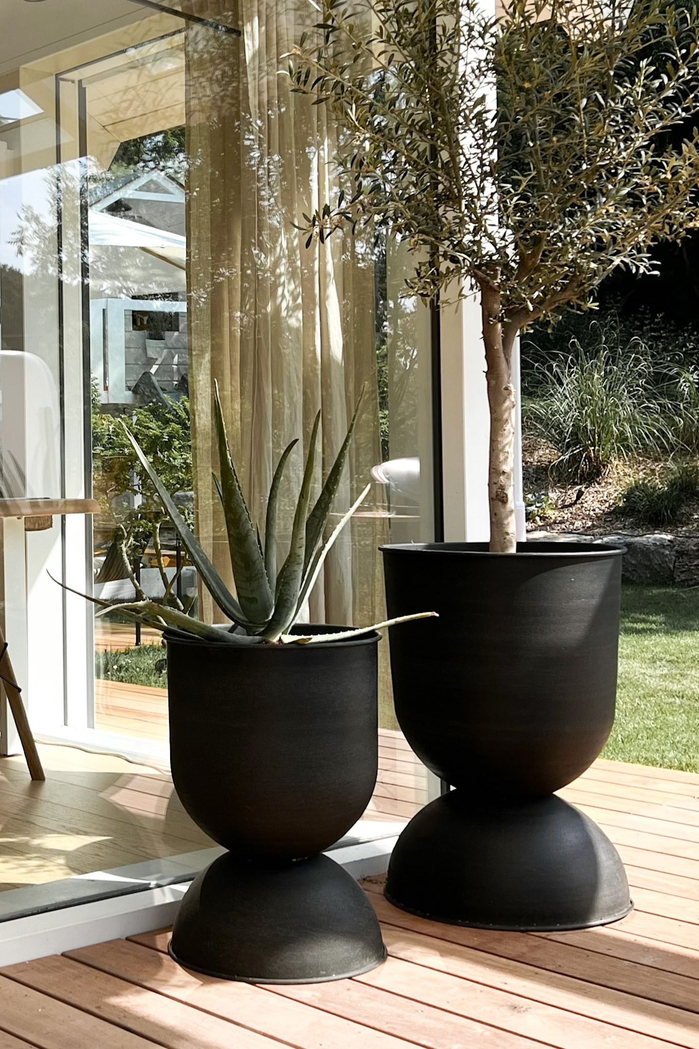 Macetas para exteriores: dos grandes macetas Hourglass de Ferm Living en una terraza.