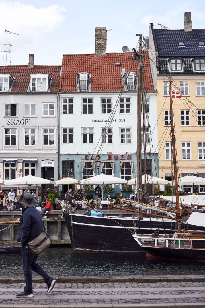 El puerto de Nyhavn es una visita obligada en cualquier recorrido por Copenhague. Aquí puedes ver a alguien paseando entre los coloridos edificios del puerto. 