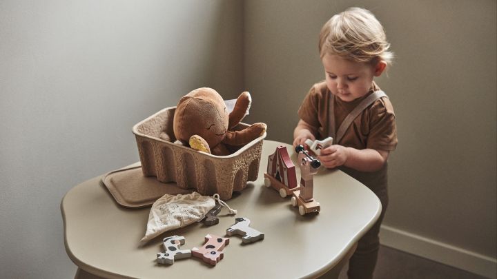 En una habitación infantil es importante dar cabida tanto a lo creativo como a lo práctico. Aquí encontramos un bebé jugando con bloques en la mesa infantil Slope en beige, de Ferm Living.