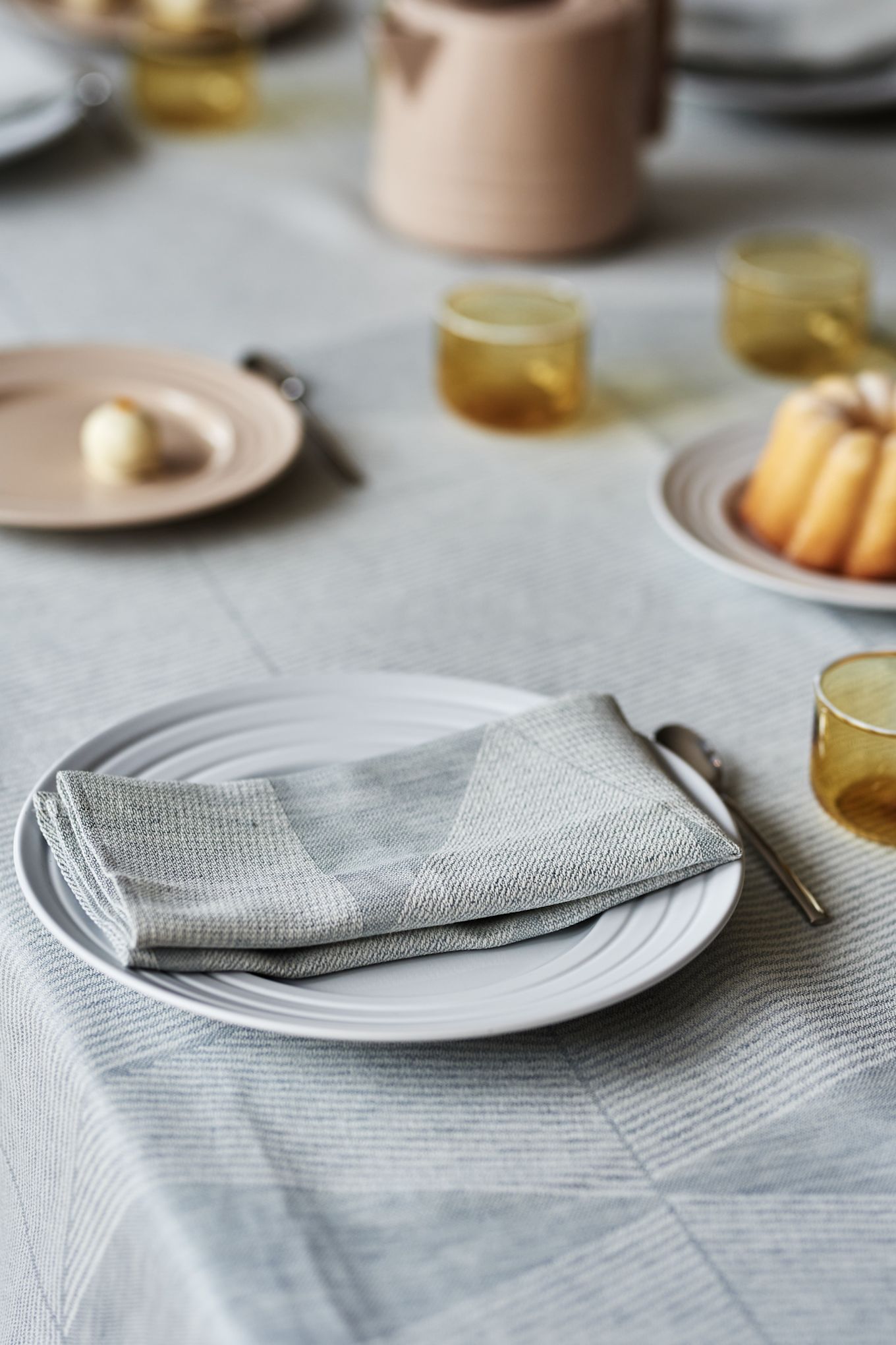 Una elegante idea para poner la mesa en suaves tonos pastel con un mantel azul cielo de NJRD y delicados elementos en beige y amarillo. 