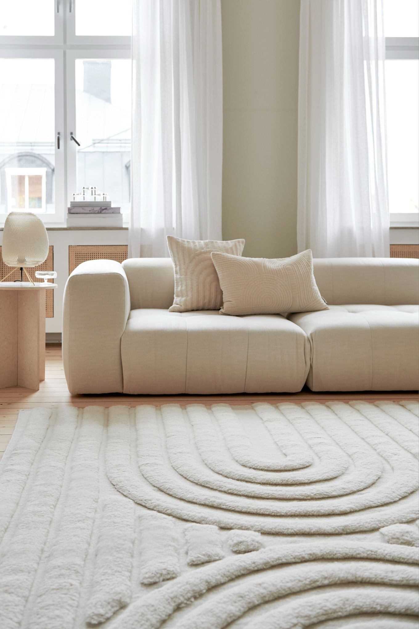 Alfombras para el salón: la alfombra de lana Curve en tonos claros de Classic Collection está colocada frente a un sofá en un sal�ón luminoso y lleno de luz natural.