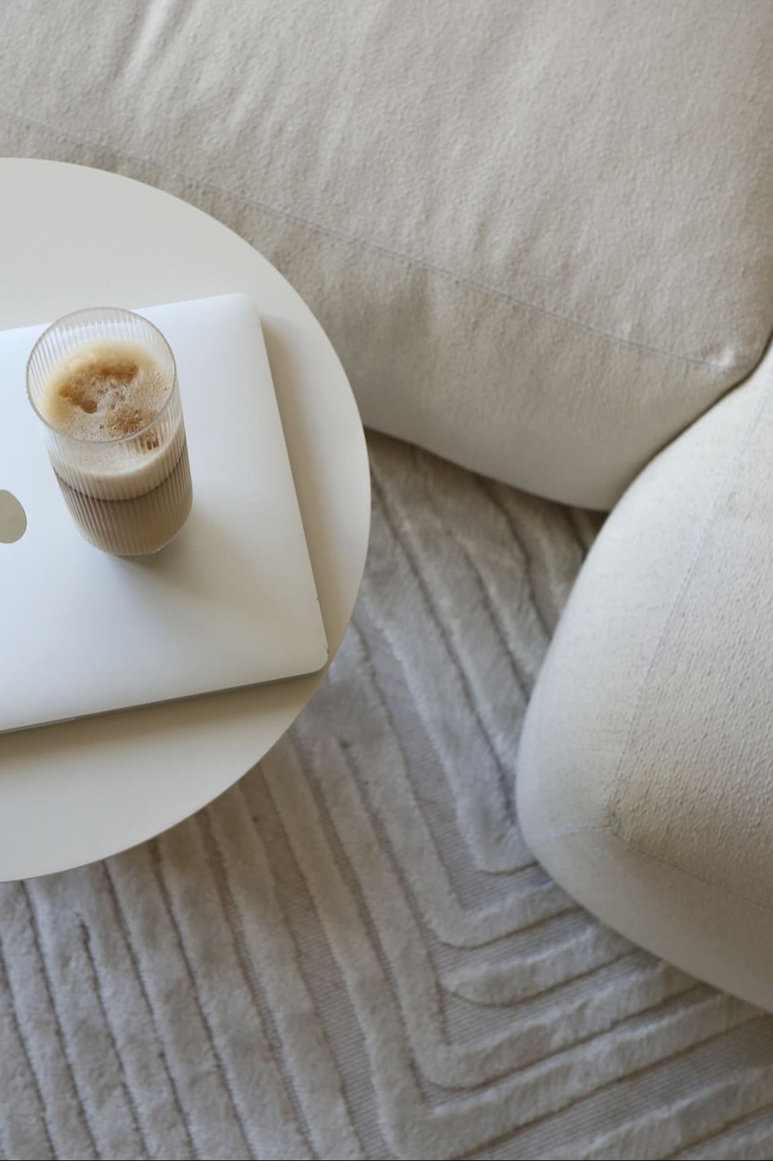 Aquí puedes ver un latte macchiato perfectamente preparado en un vaso de larga bebida de la colección Ripple de Ferm Living, que está sobre una mesa de café al lado de un sofá de color beige en el hogar de @ellesklingen.