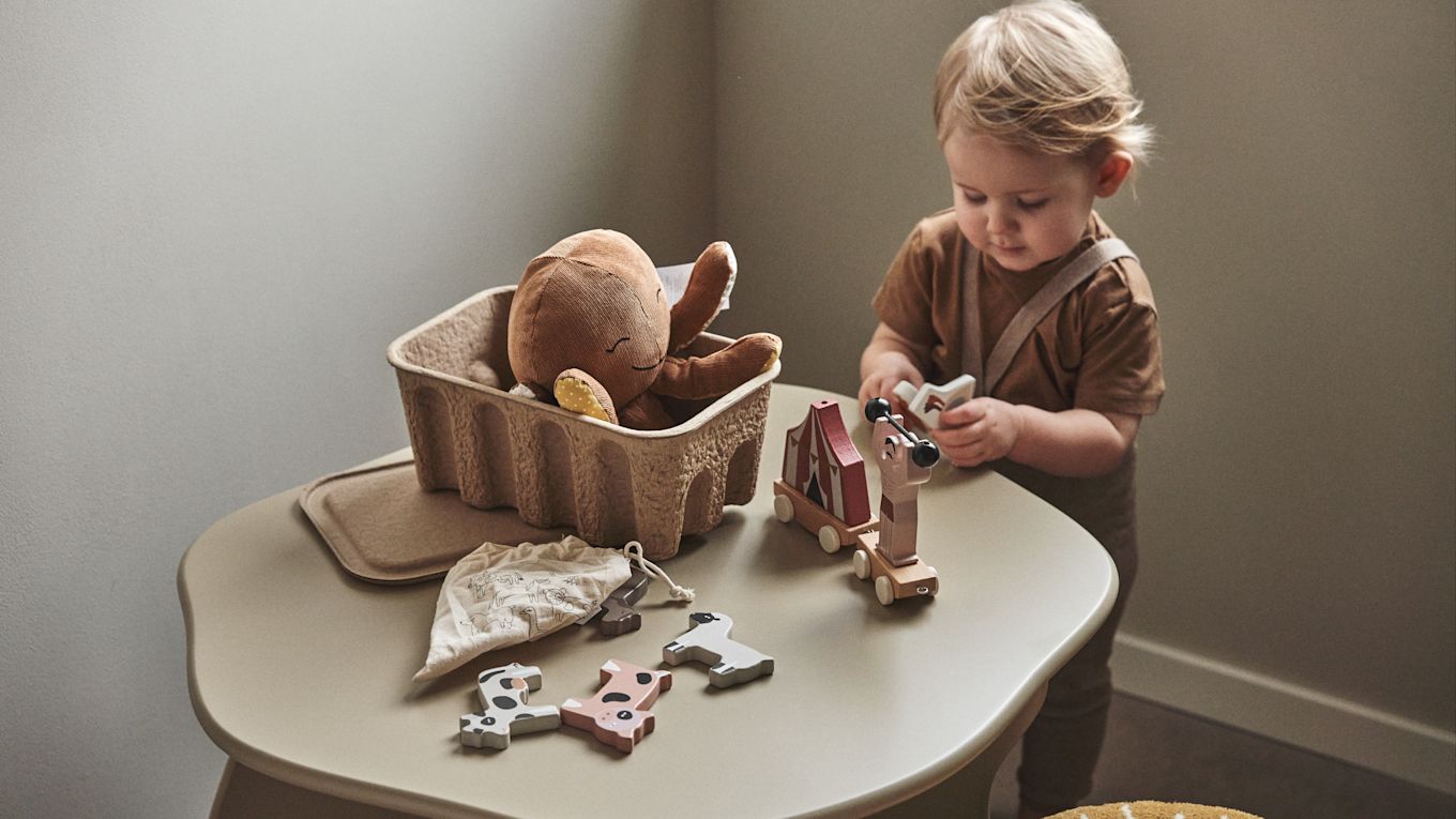 En una habitación infantil es importante dar cabida tanto a lo creativo como a lo práctico. Aquí encontramos un bebé jugando con bloques en la mesa infantil Slope en beige, de Ferm Living.