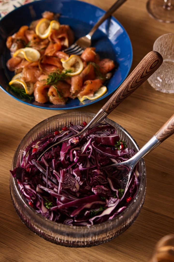 Ensalada de col roja servida en un tazón de vidrio de Iittala y salmón ahumado en frío en un plato azul Teema.