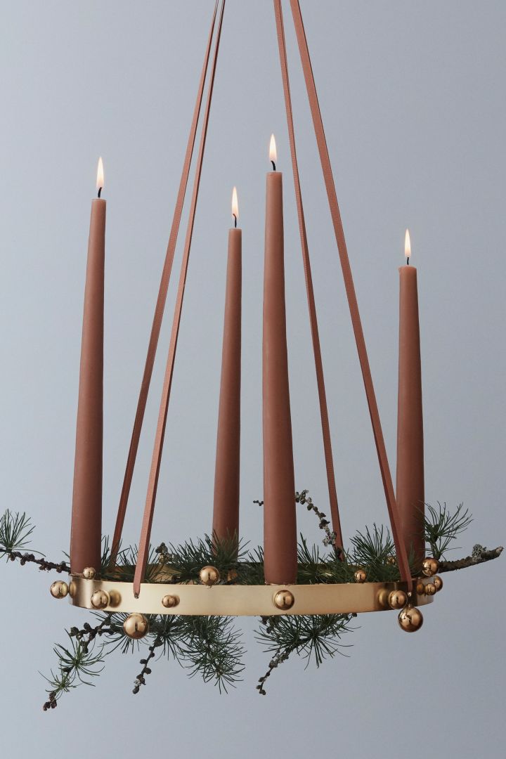 Inspírate con bonitos candelabros de adviento para la Navidad: aquí ves el elegante y festivo candelabro de adviento Pearl en oro de OYOY, acompañado de ramas de abeto.