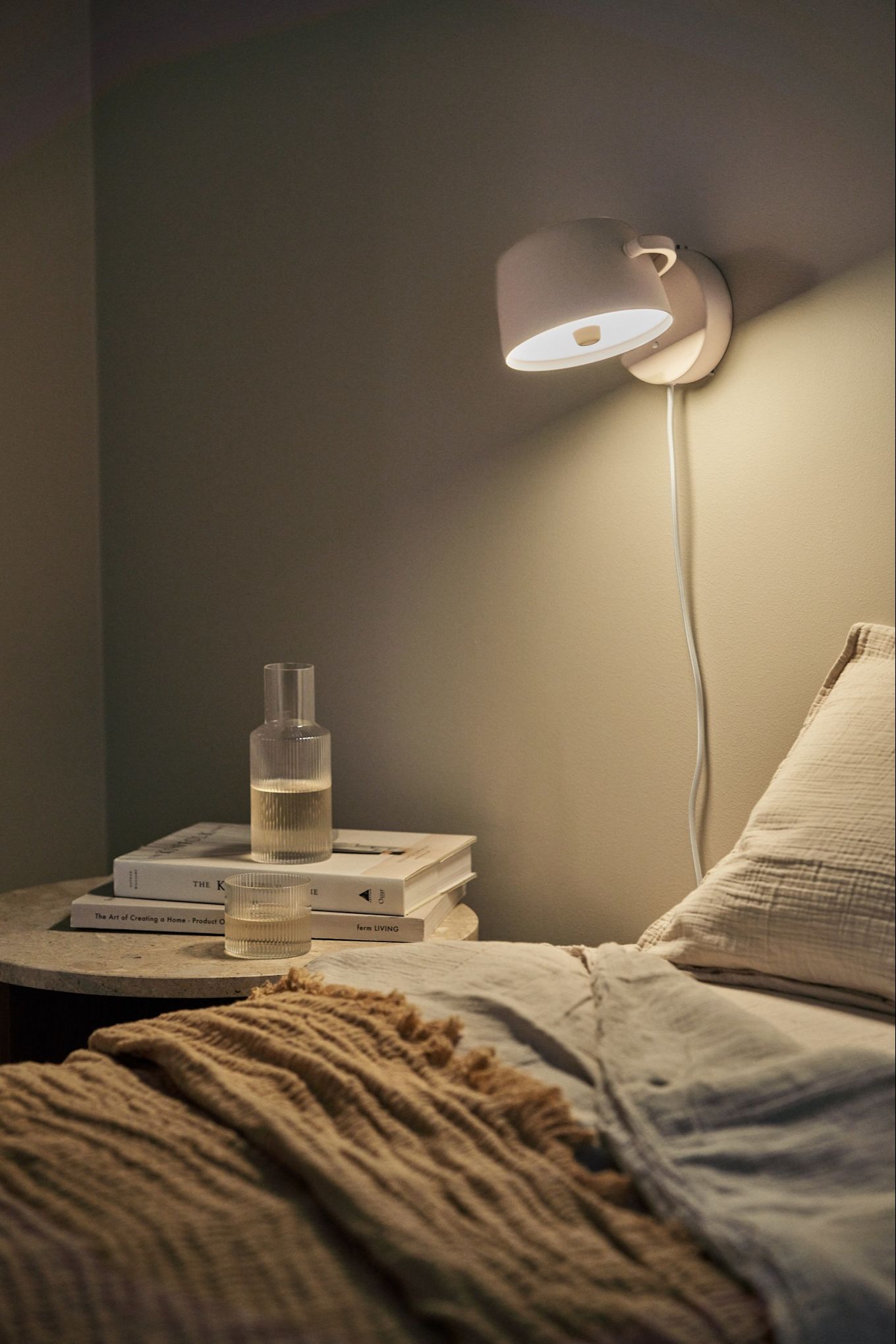 Renueva tu hogar con iluminación de pared moderna: aquí puedes ver la lámpara de pared Halo de Scandi Living en beige, colocada sobre la pared encima de una cama.