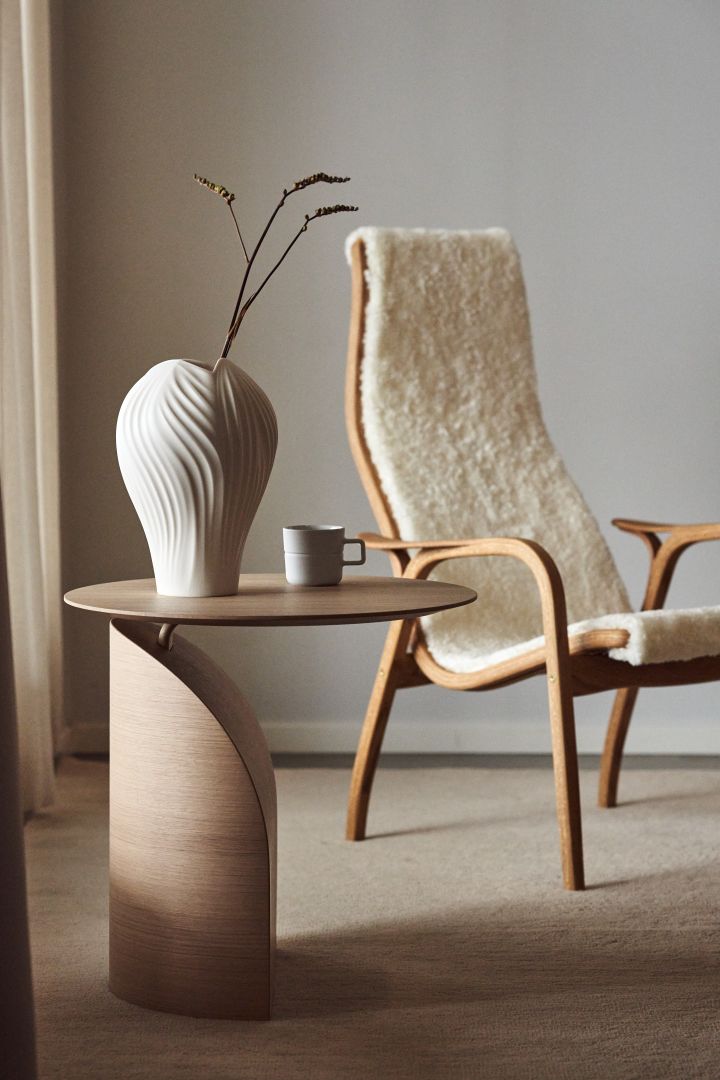 Aquí puedes ver la mesa Savoa y el sillón Lamino con piel de oveja blanca y madera de roble de la marca sueca de muebles Swedese.