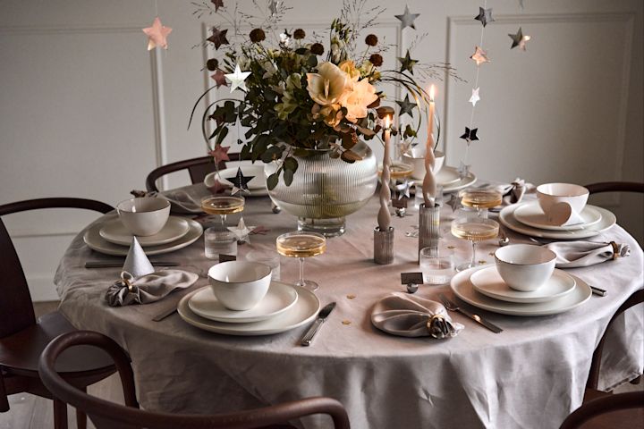 Ideas para fiestas de fin de año: un lujoso servicio de mesa blanco con elementos de cristal estriado que se reflejan en los portavelas y los portavasos de Georg Jensen.