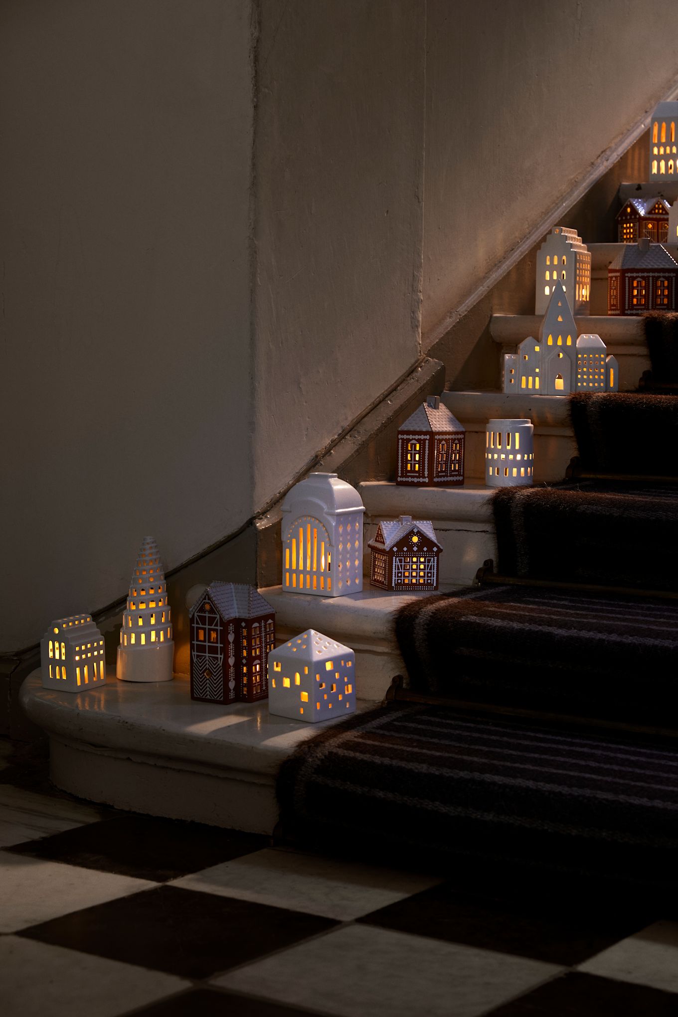 Las casas de vela de Kähler en una colección en las escaleras. Los pueblos iluminados por velas son decoraciones navideñas muy populares en 2024.