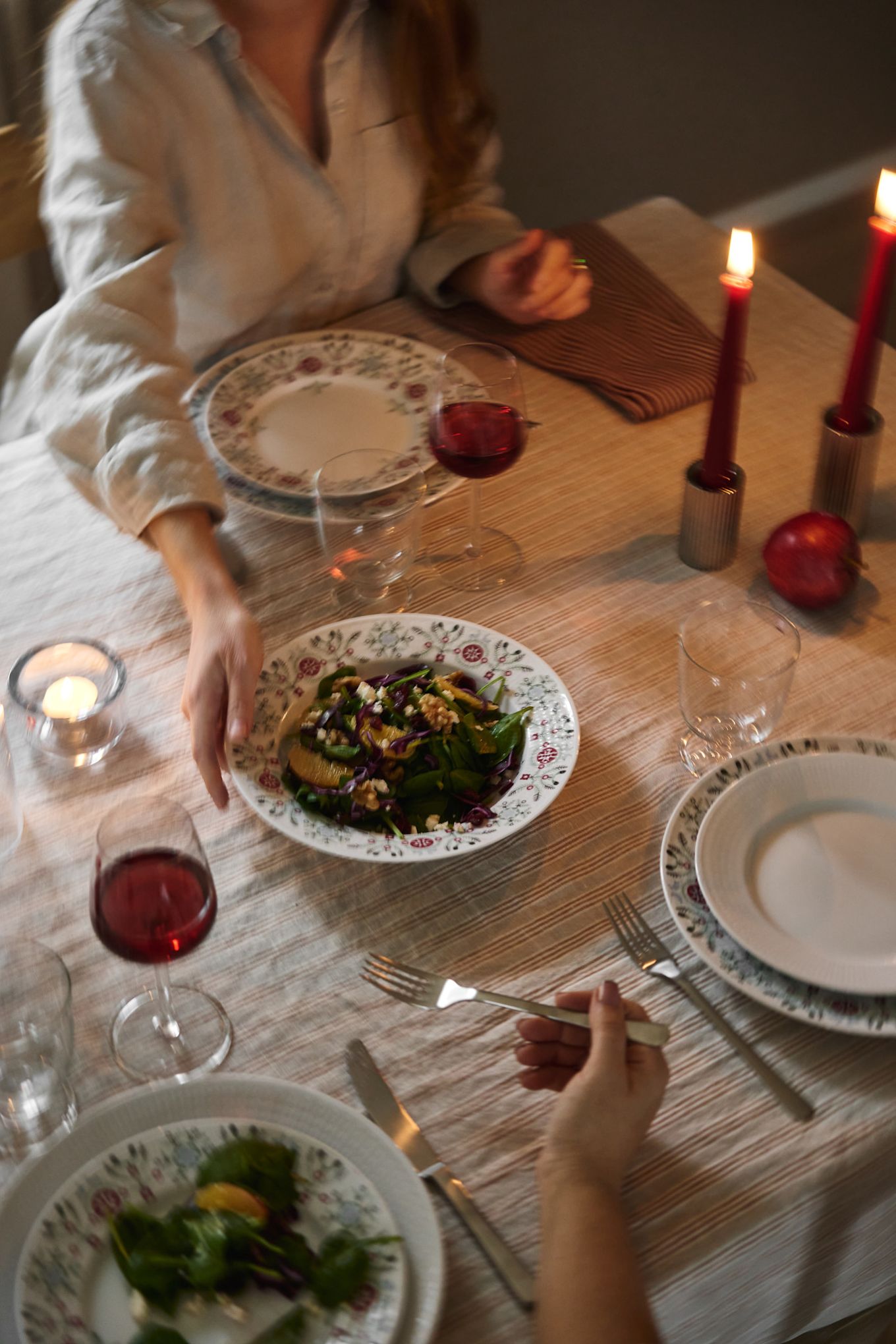 Una mano pasa una ensalada de invierno por la mesa como parte de una idea escandinava para poner la mesa en Navidad.