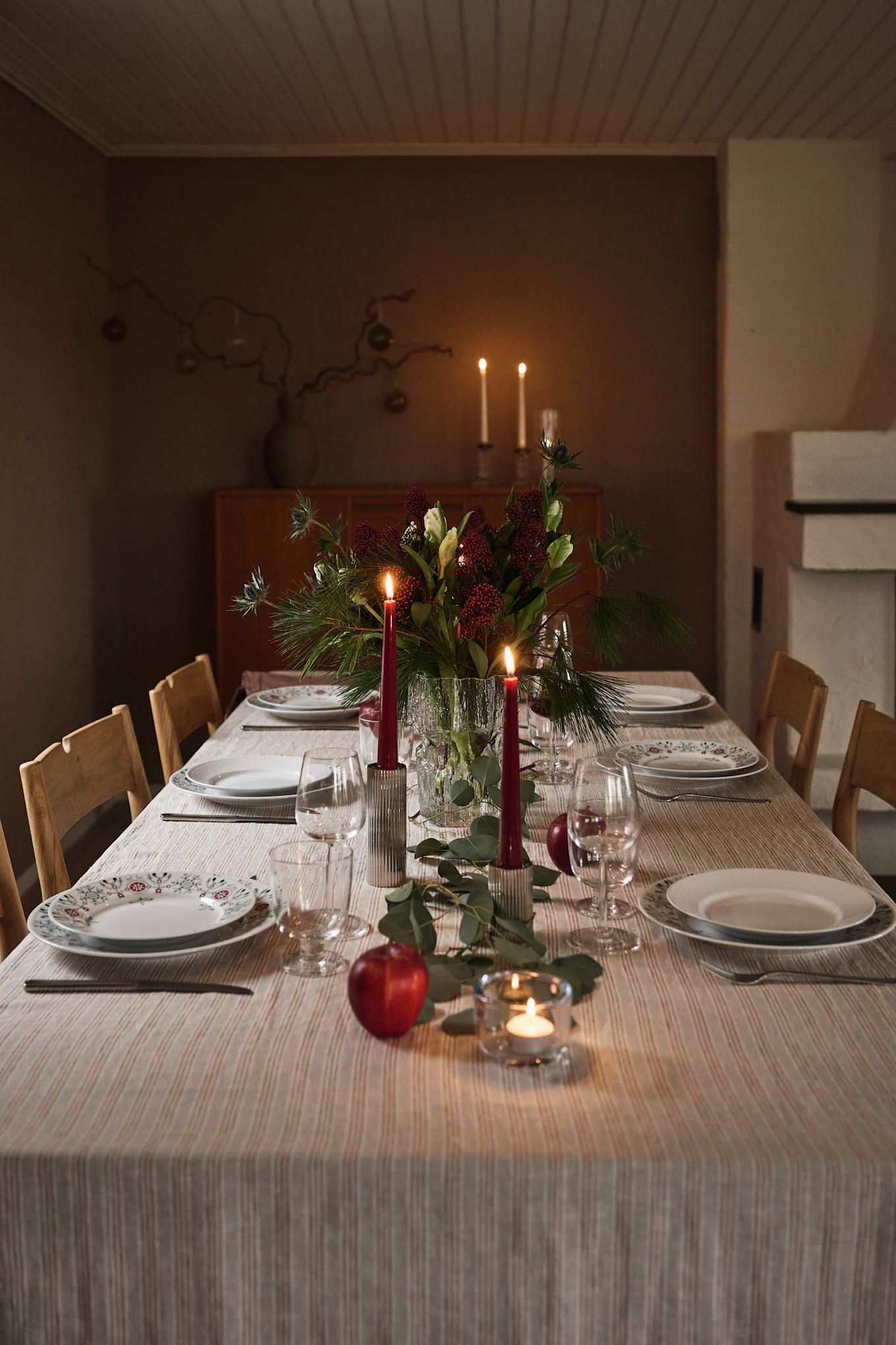 Una idea atmosférica y sencilla para poner la mesa en Navidad con velas rojas y vajilla navideña estampada.