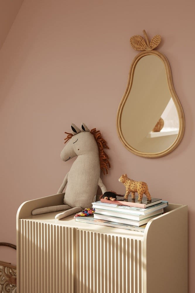 El cojín Safari Horse de Ferm Living se encuentra sobre una cómoda en una habitación infantil con el espejo Pear colgado al lado.