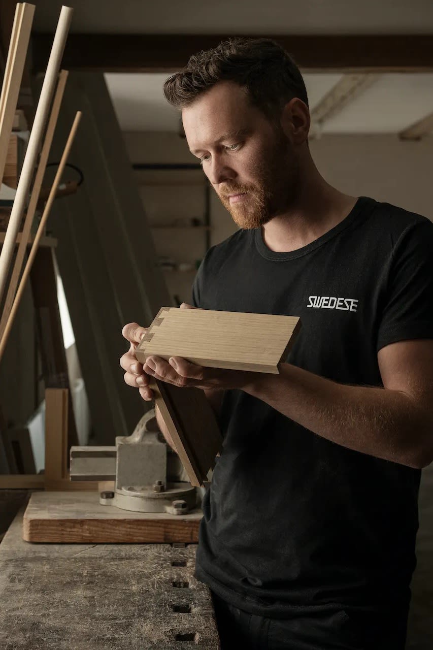 Un hombre fabricando muebles en la fábrica de muebles Swedese de Suecia.