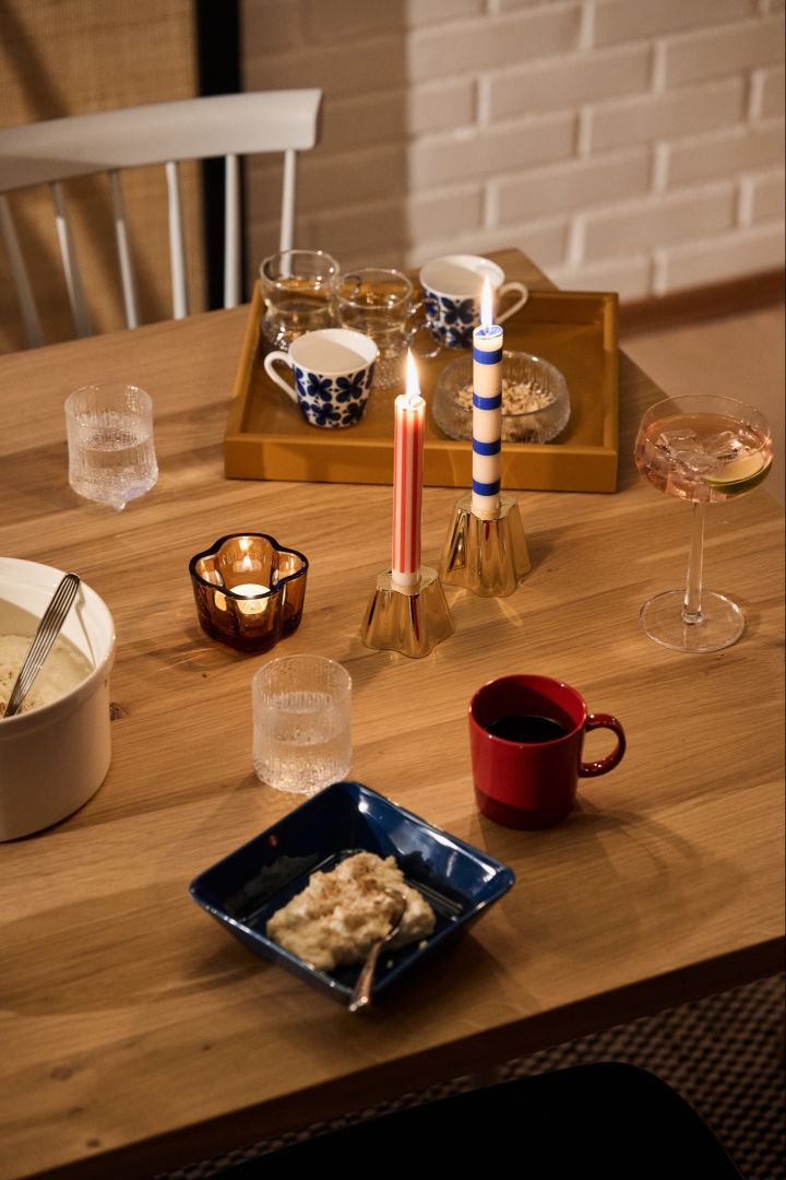 Una mesa navideña nórdica festiva en rojo y azul con un tazón azul de Ris a la Malta, una taza roja a juego y velas azules y rojas.