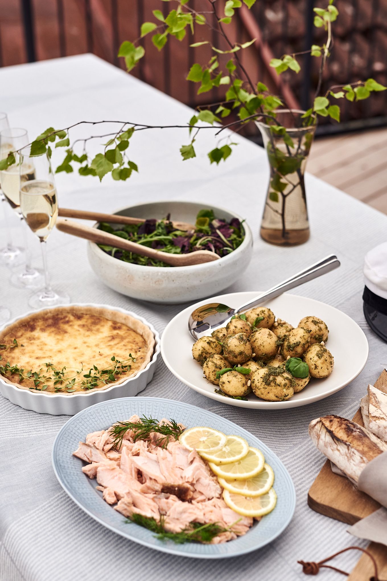 Un bufé de salmón ahumado caliente, pastel de Västerbotten, ensalada de patata al
pesto, hojas de ensalada fresca y pan crujiente caliente para el menú de tu fiesta de
verano en el jardín.