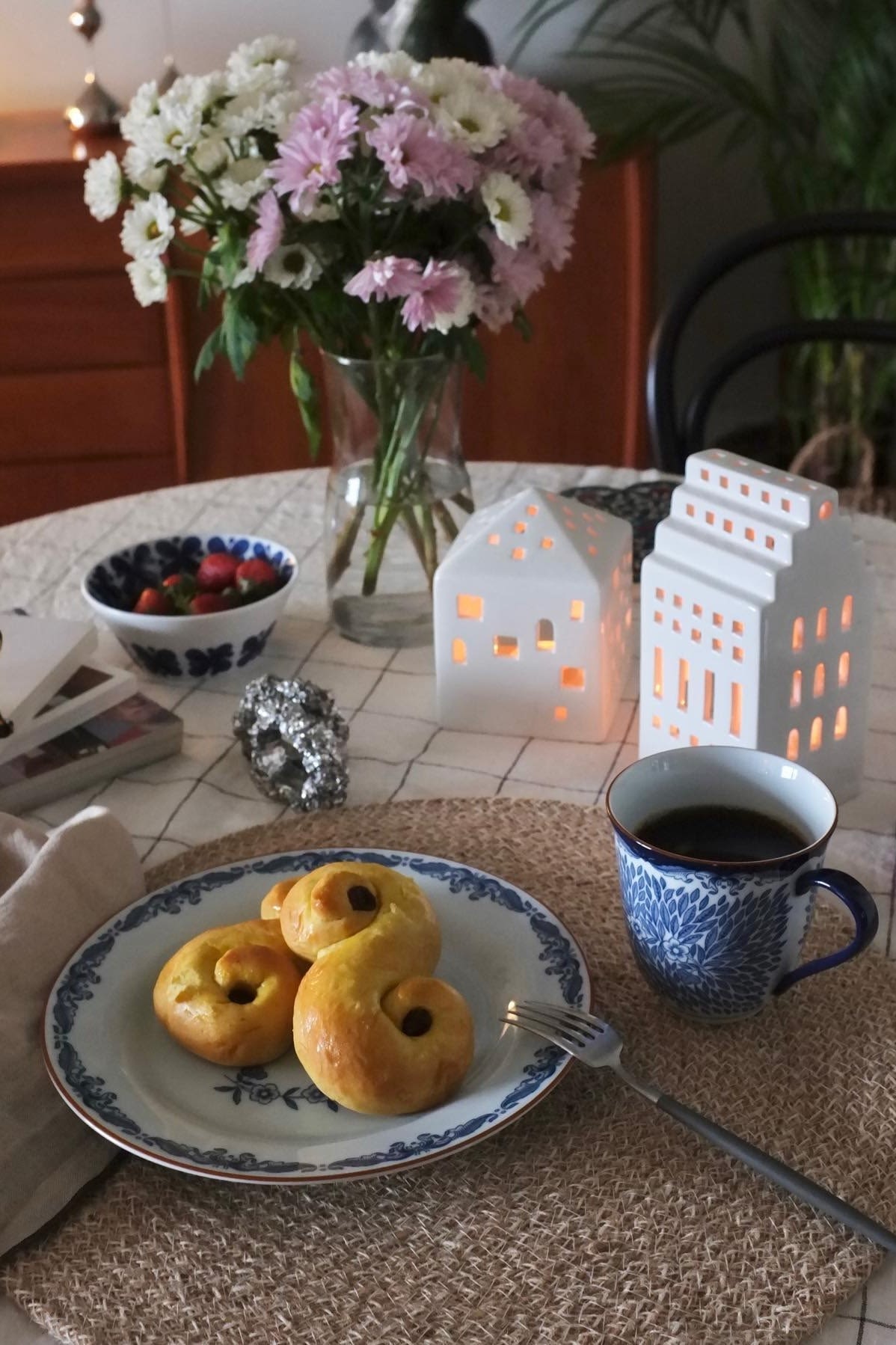 Aquí puedes ver una mesa con flores frescas y decoraciones navideñas en forma de candelabros Urbania de Kähler, junto a lussekatter suecos en un plato Ostindia de Rörstrand, en la casa de @_mariano_rivera_4242.