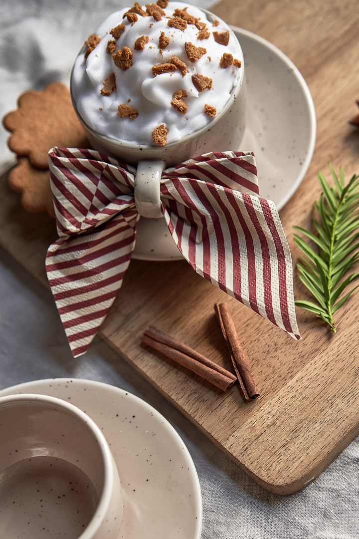 Ofrece un simple cóctel navideño con canela, café y galletas de jengibre en la taza Freckle de Scandi Living, acompañada de la servilleta Lines de Cooee Design doblada en forma de lazo.