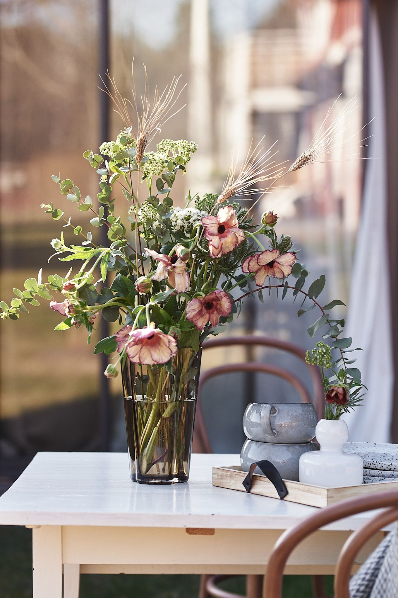 El jarrón recto alto Aalto de Iittala en cristal de color marrón ahumado con un ramo de flores de Blombruket. 